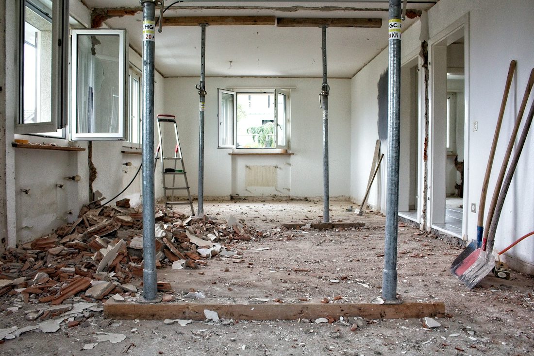 Unfinished room with temporary support posts and debris on the floor
