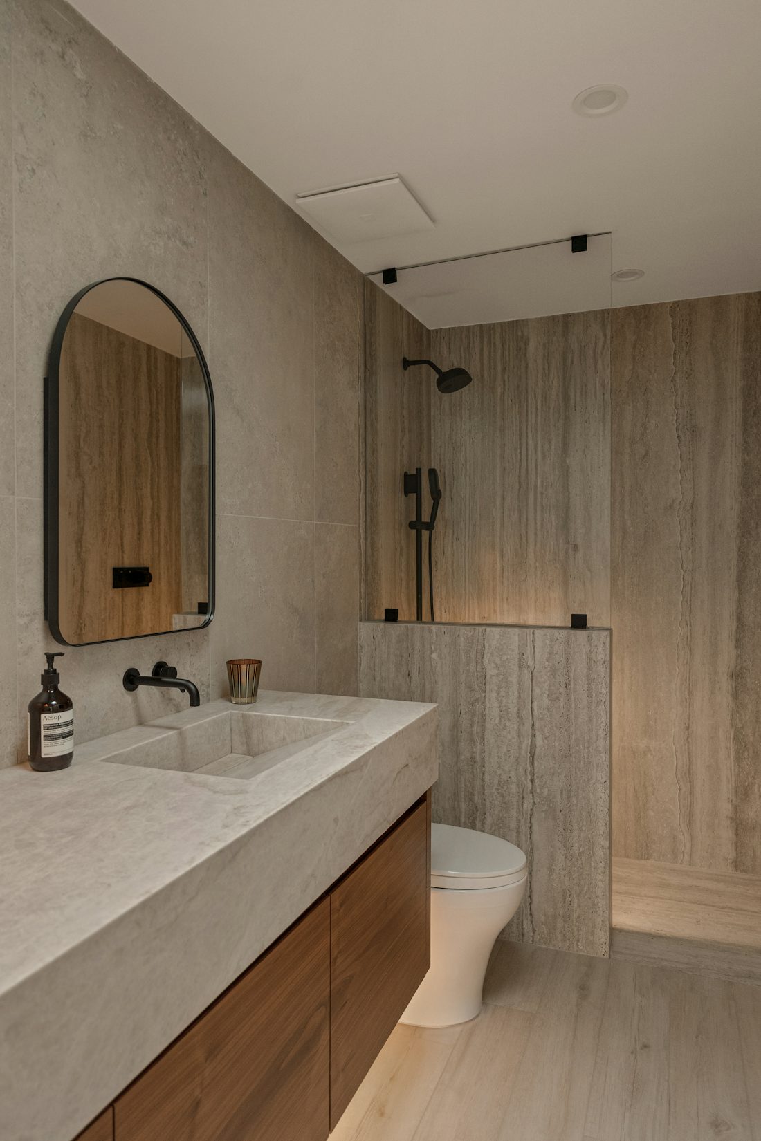 Finished bathroom with stone counter, wood vanity, and black fixtures